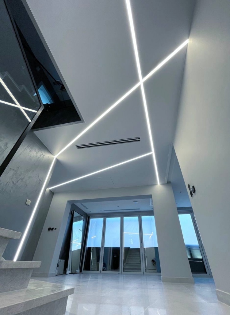 Close-up view of integrated linear LED lighting recessed into a premium white stretch ceiling. Close-up view of integrated linear LED lighting recessed into a premium white stretch ceiling.