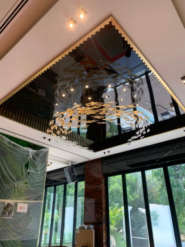 Custom black glossy stretch ceiling with rounded corners and a large sculptural chandelier creating dramatic reflections in a luxury Dubai interior. Custom black glossy stretch ceiling with rounded corners and a large sculptural chandelier creating dramatic reflections in a luxury Dubai interior.