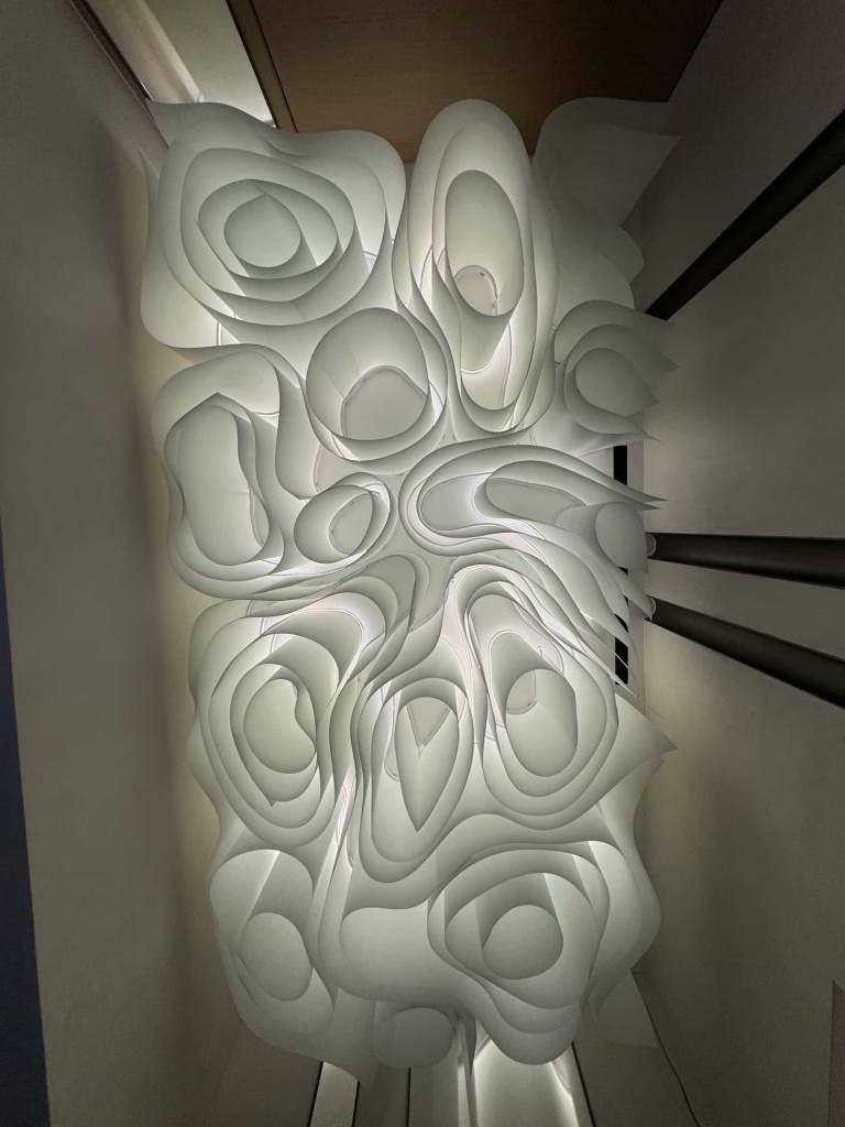 Close-up view of the three-dimensional architectural fabric ceiling highlighting its elegant curves, layered construction and integrated indirect lighting. Close-up view of the three-dimensional architectural fabric ceiling highlighting its elegant curves, layered construction and integrated indirect lighting.