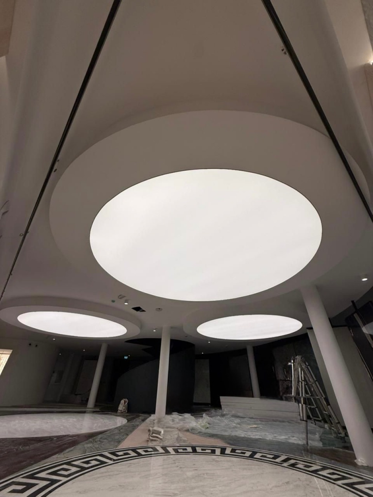 Large circular bespoke luminous ceiling panels installed in a commercial interior with seamless stretch ceiling technology. Large circular bespoke luminous ceiling panels installed in a commercial interior with seamless stretch ceiling technology.