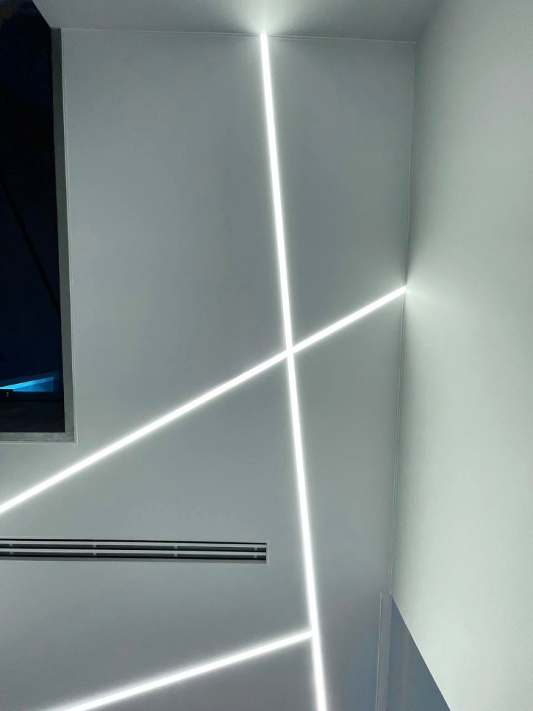 Wide view of a seamless white stretch ceiling with custom LED light lines installed in a contemporary Dubai residence. Wide view of a seamless white stretch ceiling with custom LED light lines installed in a contemporary Dubai residence.