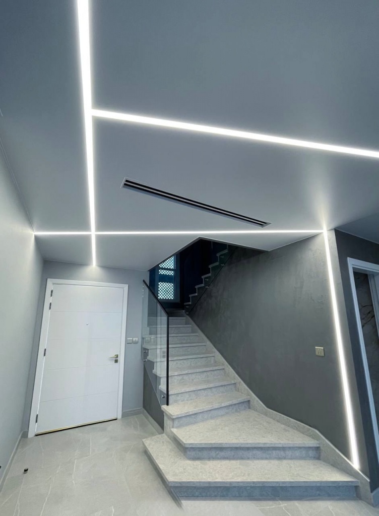 Custom stretch ceiling installation combining clean white surfaces with recessed LED light lines for a contemporary interior. Custom stretch ceiling installation combining clean white surfaces with recessed LED light lines for a contemporary interior.