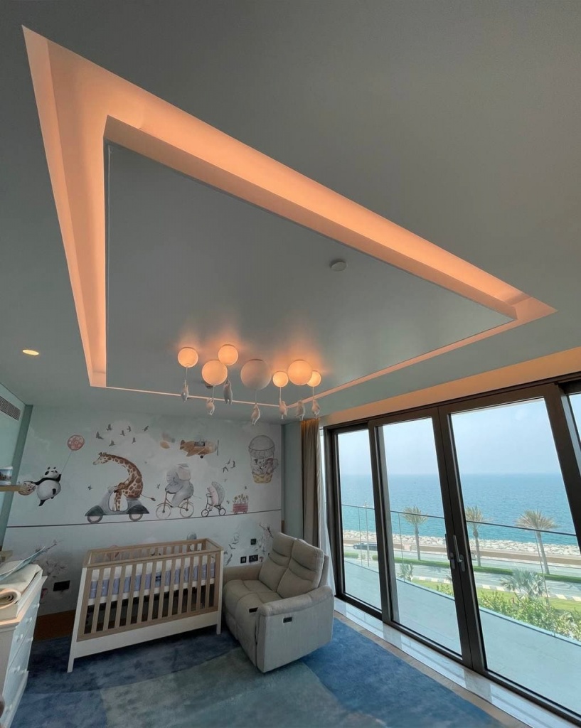 Custom white stretch ceiling with integrated perimeter LED lighting installed in a luxury nursery overlooking the Dubai waterfront. Custom white stretch ceiling with integrated perimeter LED lighting installed in a luxury nursery overlooking the Dubai waterfront.