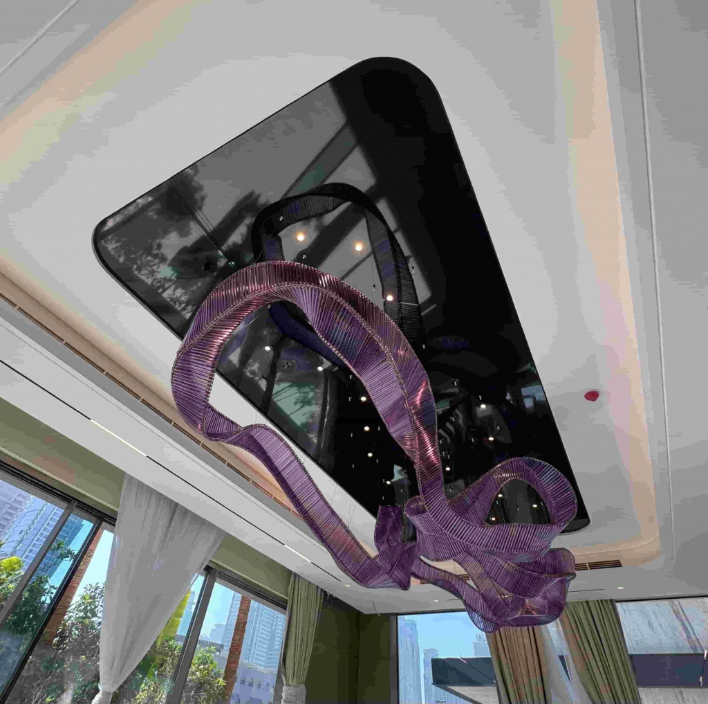 High-gloss black mirror-effect ceiling installed above a bespoke suspended chandelier, creating strong reflections and visual depth in a luxury residential interior. High-gloss black mirror-effect ceiling installed above a bespoke suspended chandelier, creating strong reflections and visual depth in a luxury residential interior.