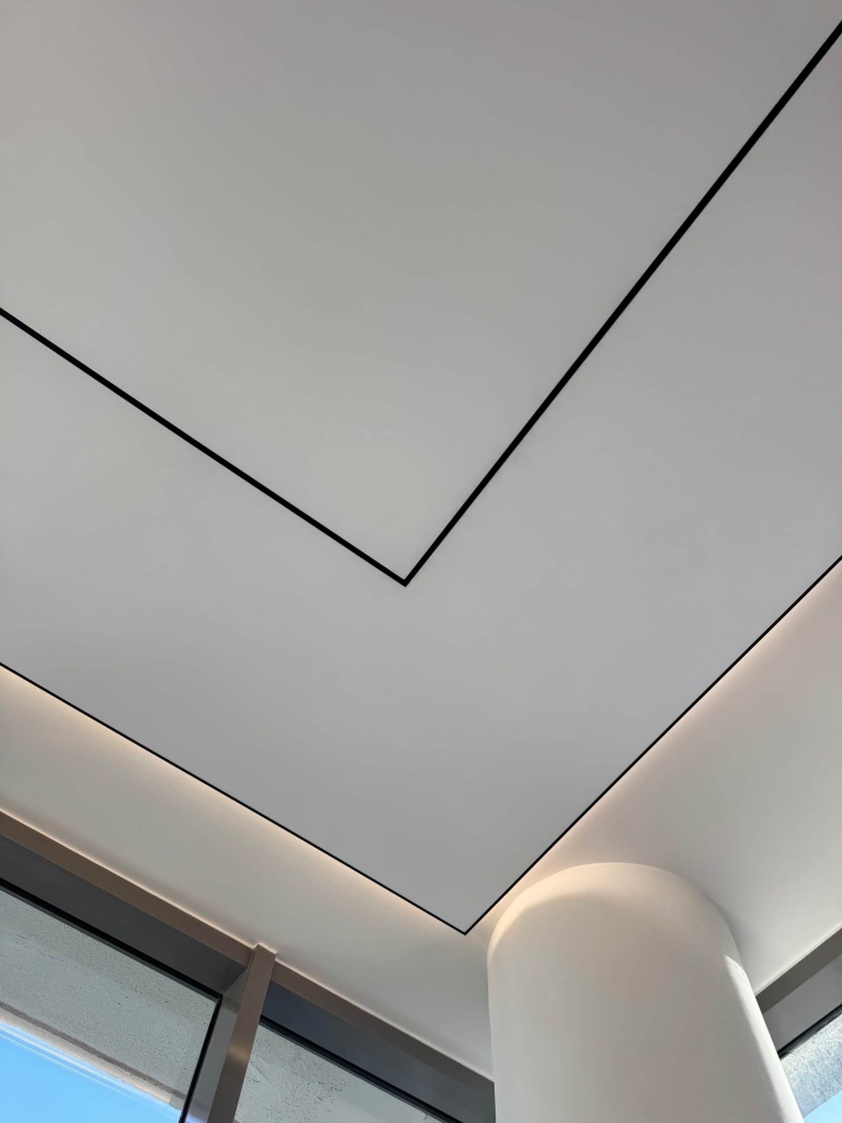 Premium white stretch ceiling with integrated magnetic track lighting and seamless architectural detailing. Premium white stretch ceiling with integrated magnetic track lighting and seamless architectural detailing.