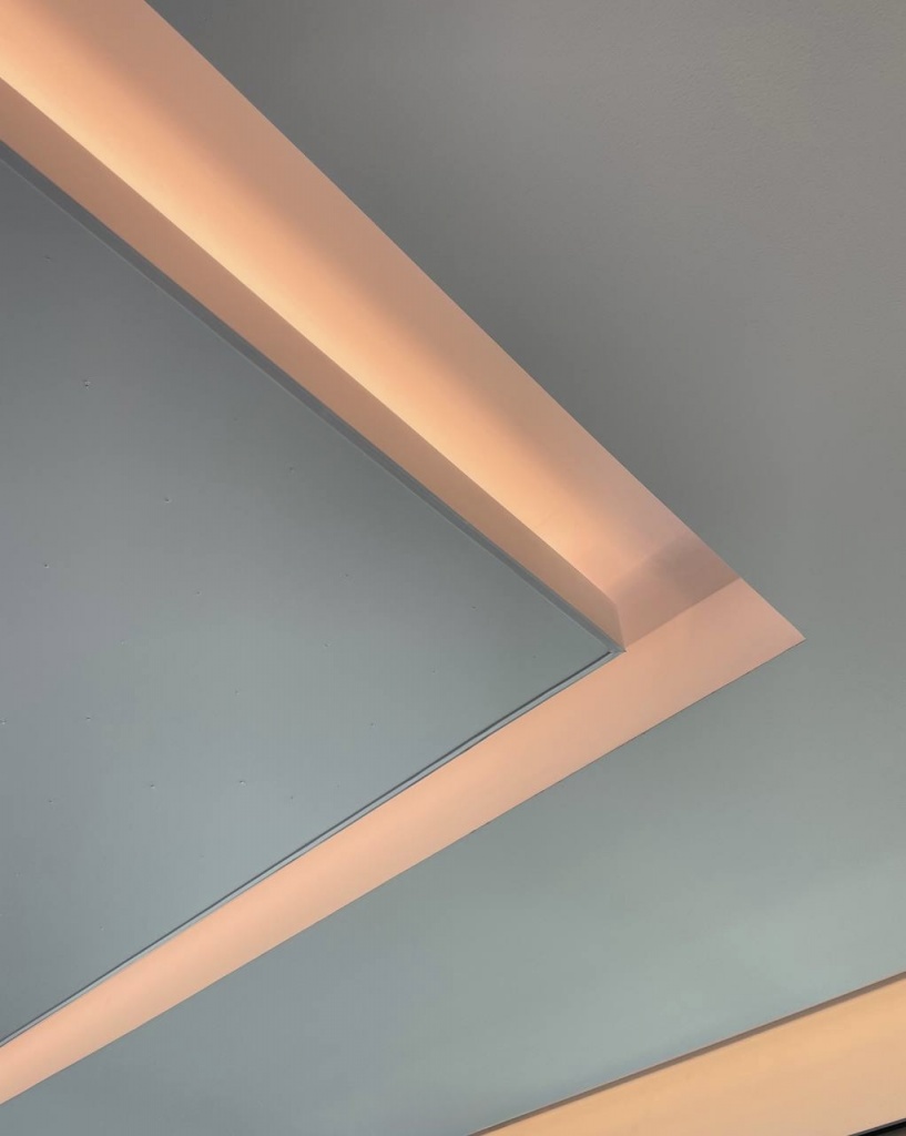 Architectural detail of a floating stretch ceiling featuring concealed LED cove lighting, creating a soft indirect glow and a clean minimalist appearance in a luxury Dubai villa. Architectural detail of a floating stretch ceiling featuring concealed LED cove lighting, creating a soft indirect glow and a clean minimalist appearance in a luxury Dubai villa.
