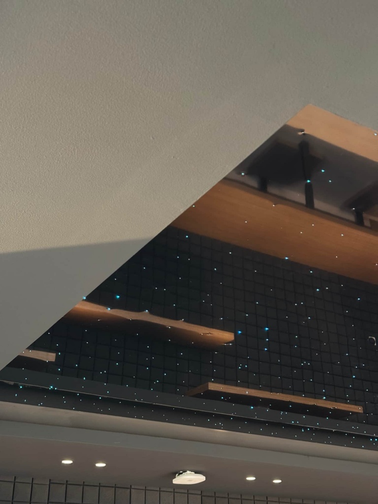 Premium gaming room featuring a mirror-finish black stretch ceiling with integrated fiber optic stars and architectural lighting. Premium gaming room featuring a mirror-finish black stretch ceiling with integrated fiber optic stars and architectural lighting.