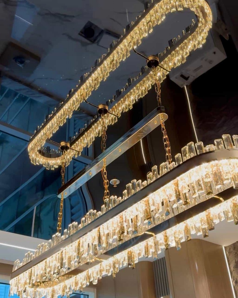 Modern mirror-effect stretch ceiling integrated with architectural lighting and decorative chandelier in an executive office. Modern mirror-effect stretch ceiling integrated with architectural lighting and decorative chandelier in an executive office.