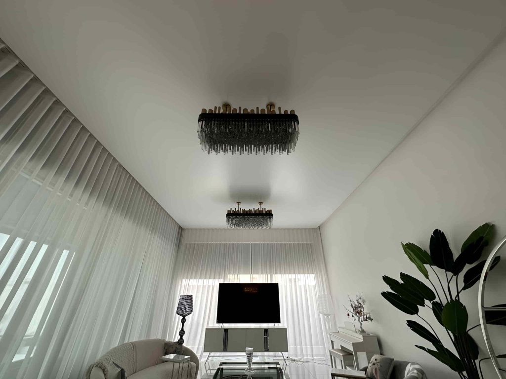 Clean white stretch ceiling installed above a contemporary dining area with integrated HVAC systems and minimalist architectural detailing. Clean white stretch ceiling installed above a contemporary dining area with integrated HVAC systems and minimalist architectural detailing.