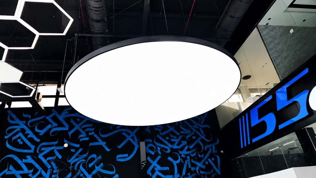 Large suspended circular light ceiling feature with uniform LED illumination installed as a focal point in a modern commercial interior. Large suspended circular light ceiling feature with uniform LED illumination installed as a focal point in a modern commercial interior.