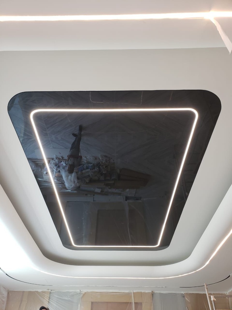 Contemporary black glossy stretch ceiling featuring an illuminated rounded rectangular outline and perimeter LED lighting for a dramatic modern interior. Contemporary black glossy stretch ceiling featuring an illuminated rounded rectangular outline and perimeter LED lighting for a dramatic modern interior.