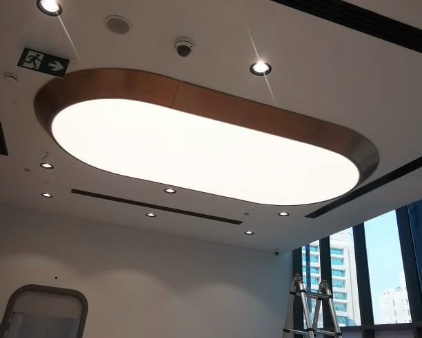 Oval illuminated ceiling panel with brushed metal trim installed in a premium commercial office interior. Oval illuminated ceiling panel with brushed metal trim installed in a premium commercial office interior.