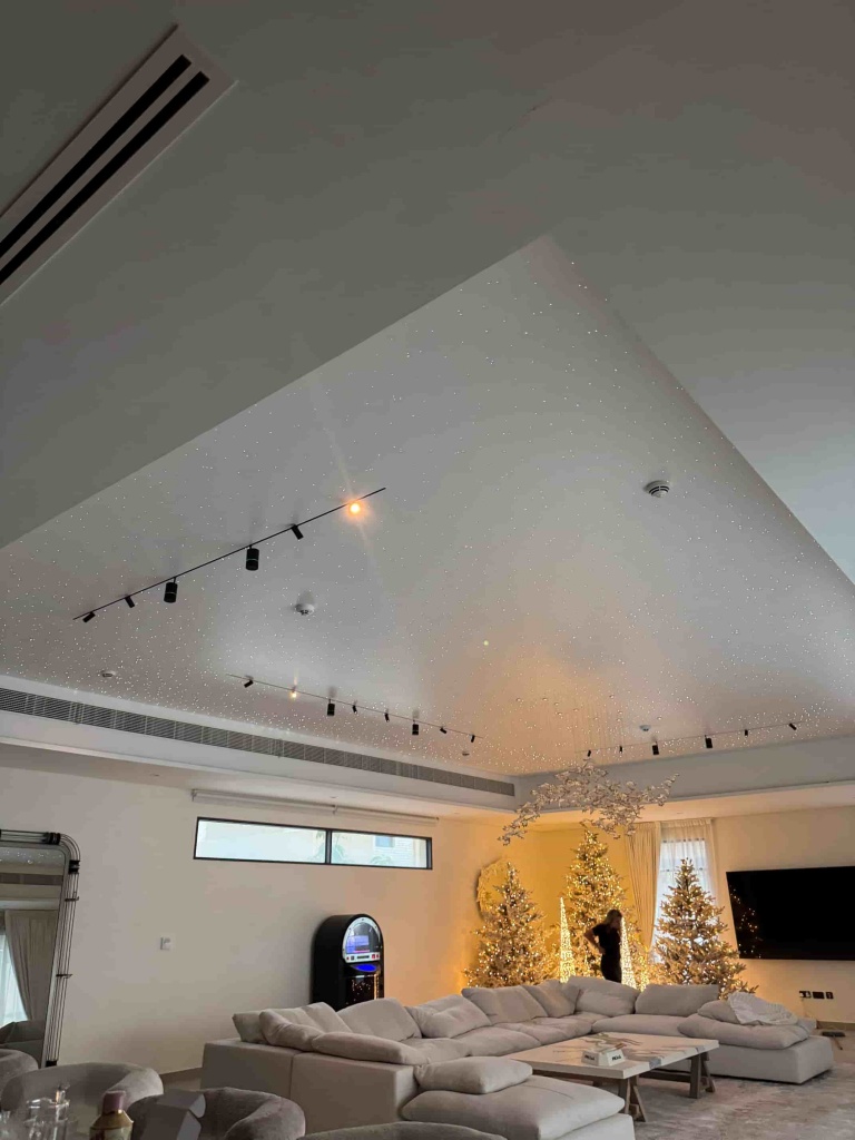 A panoramic view of a white stretch ceiling with integrated fiber optic stars installed in a luxury villa living room. The project includes magnetic track lighting and premium architectural detailing. A panoramic view of a white stretch ceiling with integrated fiber optic stars installed in a luxury villa living room. The project includes magnetic track lighting and premium architectural detailing.