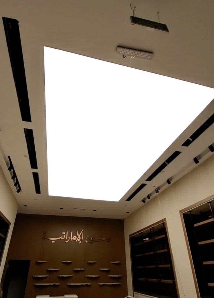 Custom-shaped illuminated stretch ceiling providing broad diffuse lighting for a modern architectural interior. Custom-shaped illuminated stretch ceiling providing broad diffuse lighting for a modern architectural interior.