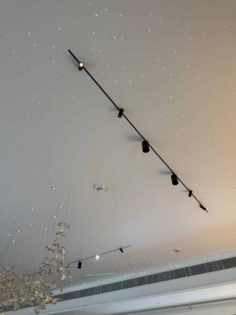 A panoramic view of a white stretch ceiling with integrated fiber optic stars installed in a luxury villa living room. The project includes magnetic track lighting and premium architectural detailing. A panoramic view of a white stretch ceiling with integrated fiber optic stars installed in a luxury villa living room. The project includes magnetic track lighting and premium architectural detailing.