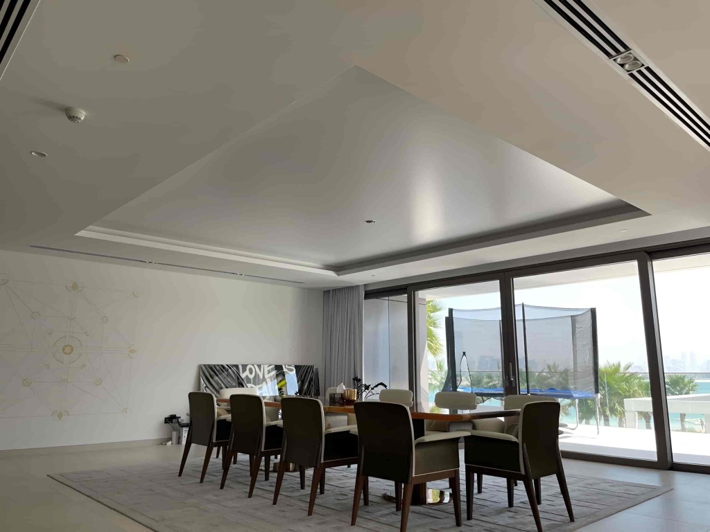 Minimalist white stretch ceiling creating a smooth continuous surface in a bright contemporary living room with decorative chandeliers. Minimalist white stretch ceiling creating a smooth continuous surface in a bright contemporary living room with decorative chandeliers.