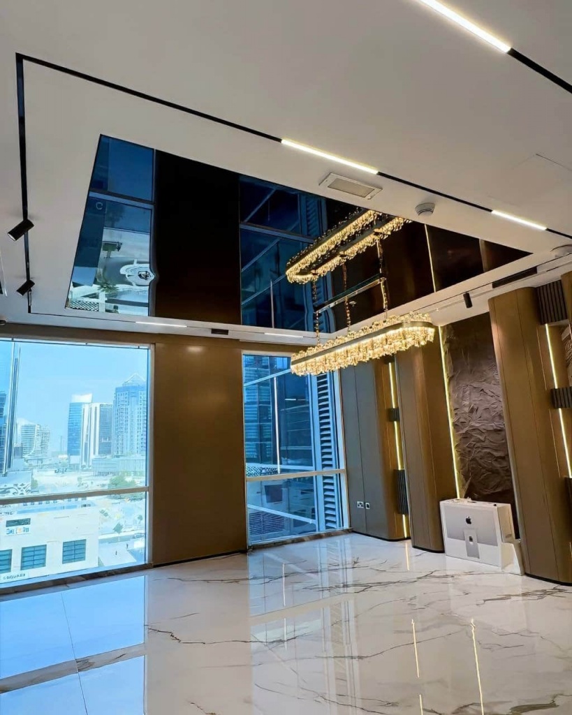 Luxury black glossy stretch ceiling with crystal chandelier reflection in a premium office interior at Bay Square. Luxury black glossy stretch ceiling with crystal chandelier reflection in a premium office interior at Bay Square.